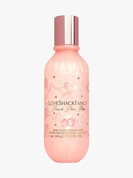 Peach colored bottle of LoveShackFancy  Peach Pom Pom Hair & Body Perfume Mist on light gray background